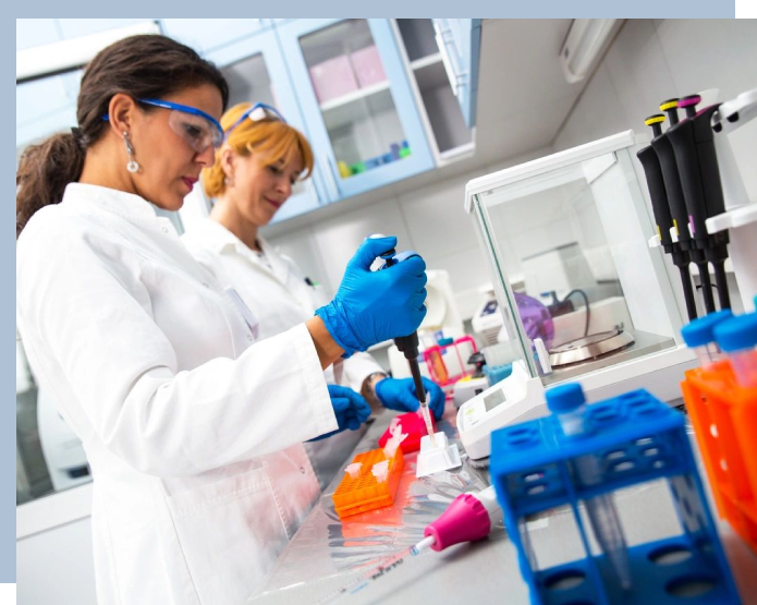 Two women in lab coats working with a blue tube.